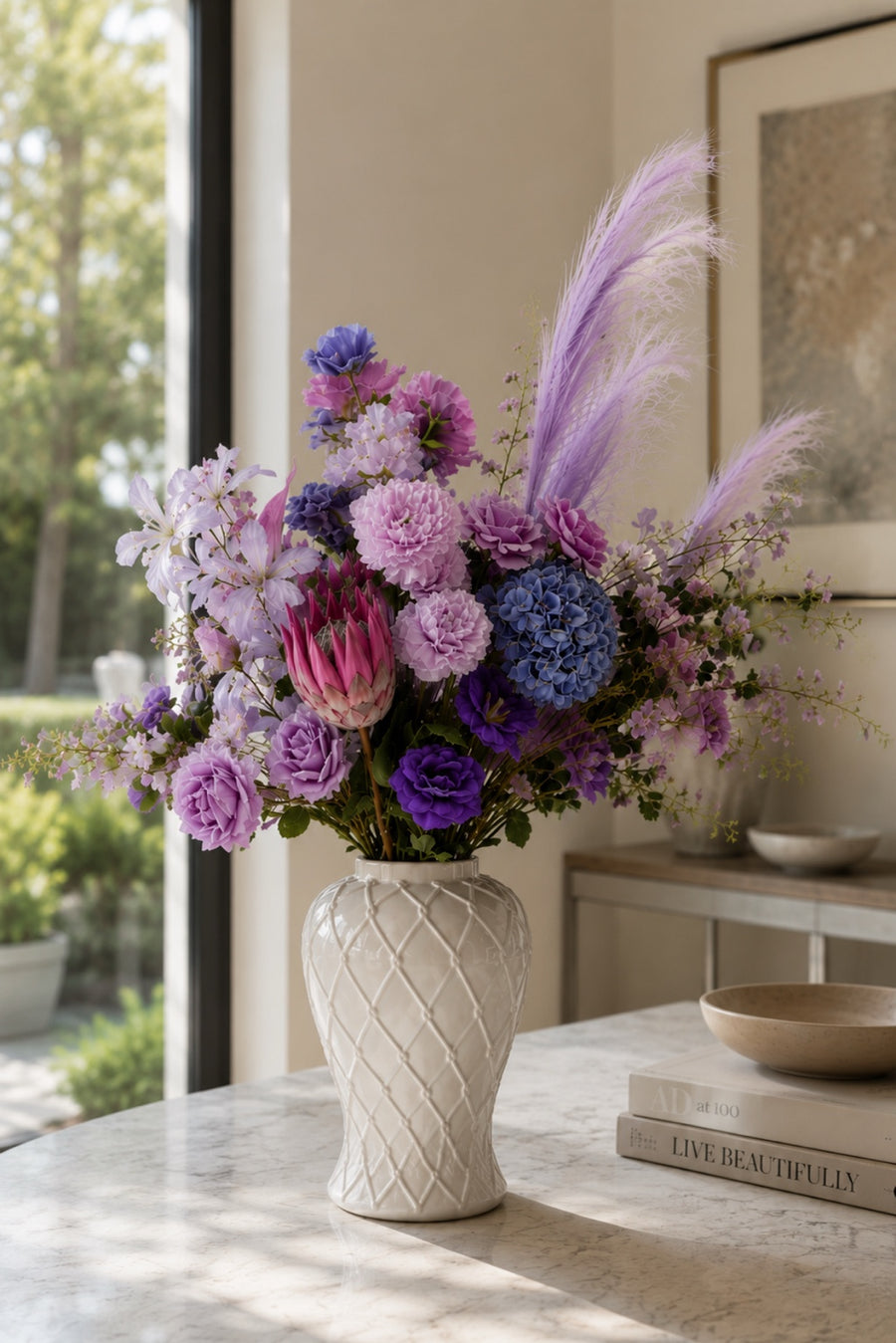 Monet-inspired Water Lily Collection artificial flower arrangement featuring pastel lavender, lilac, blush pink and soft blue blooms in a white ceramic vase, styled as elegant home décor in a bright sunlit interior.