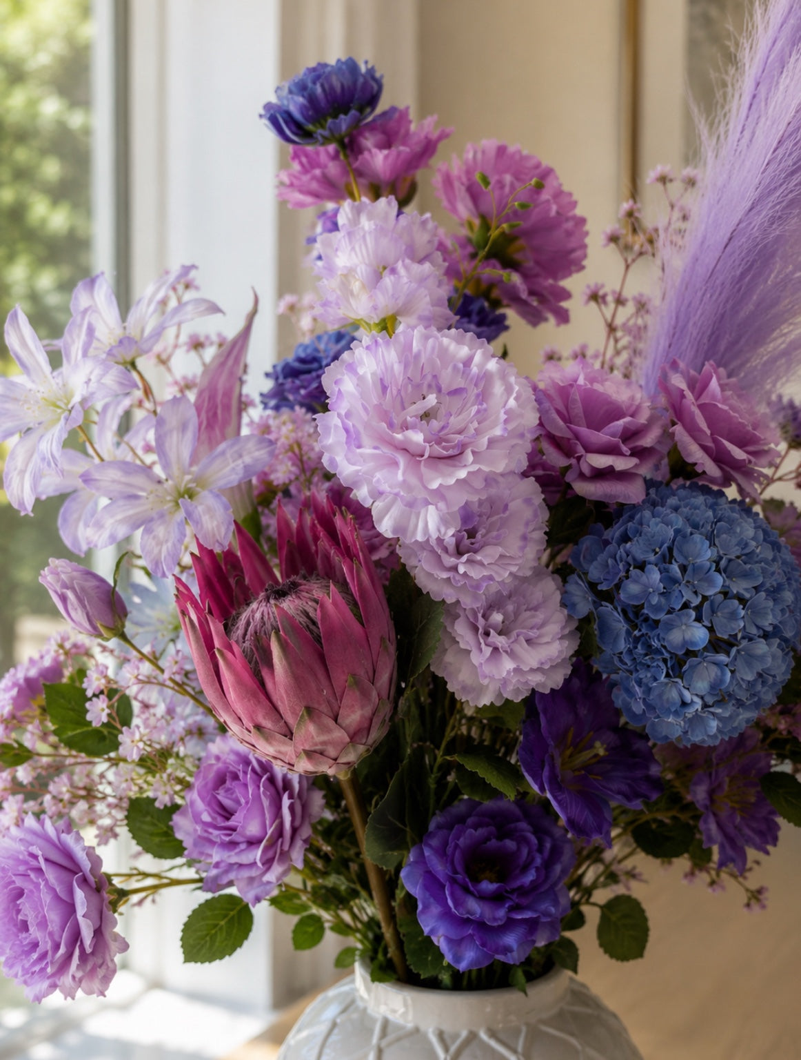 Close-up of the Water Lily Collection artificial floral arrangement featuring pastel lavender, lilac, blush pink and soft blue blooms, including hydrangea, protea and roses in a white ceramic vase.